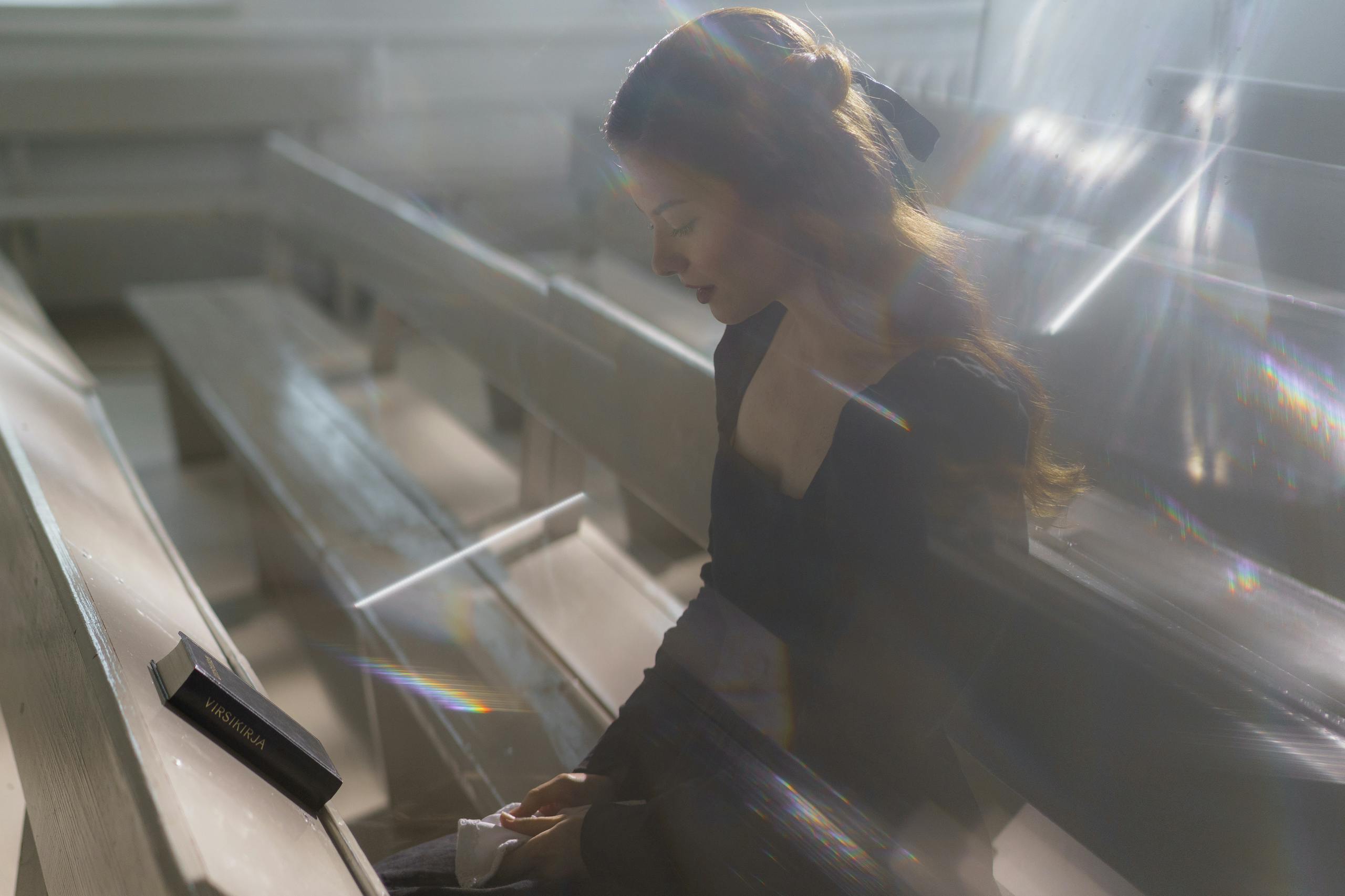 A Woman in Black Long Sleeve Shirt Sitting on Wooden Pew