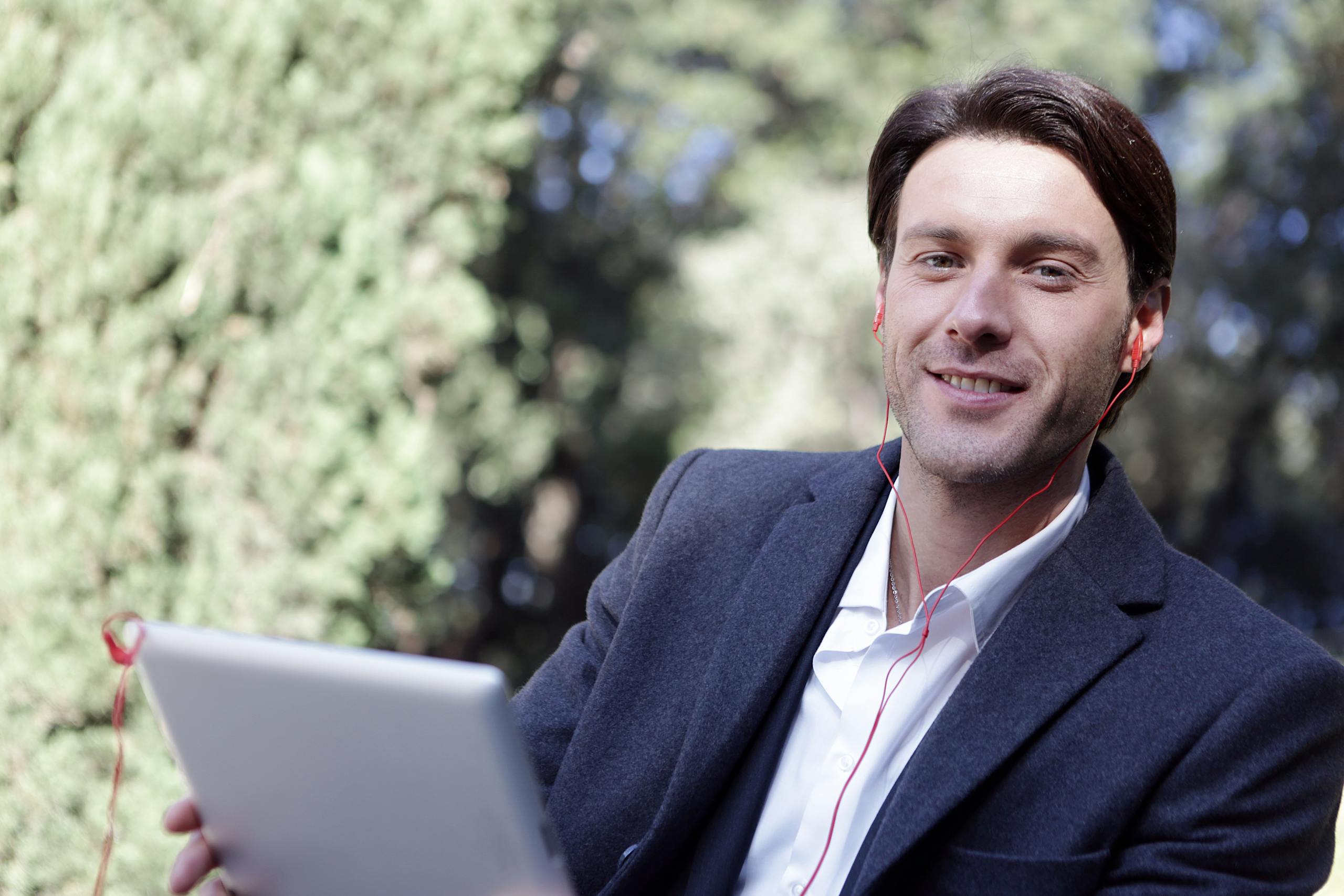 Man Holding a Silver Tablet Listening to Music